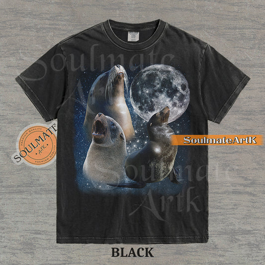 Collage of three sea lions in front of a glowing full moon and a starry night sky on a washed black shirt.