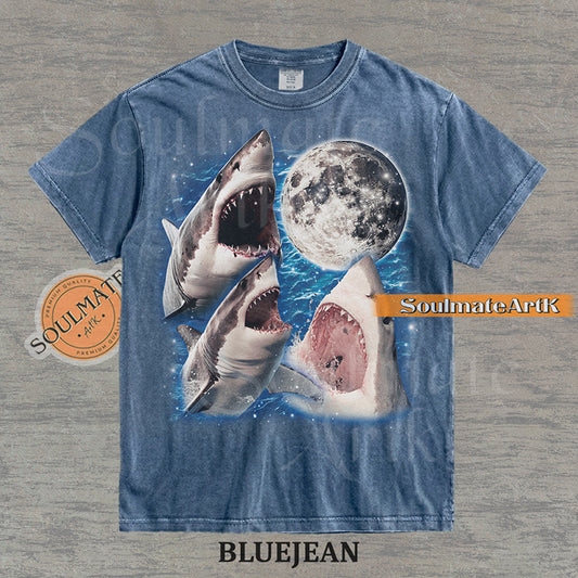 Collage of three great white sharks breaching water in front of a glowing full moon and a starry blue nebula on a washed bluejean shirt.