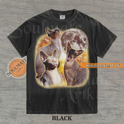 Collage of three Sphynx cats in front of a glowing moon and a golden starry nebula on a washed black shirt.