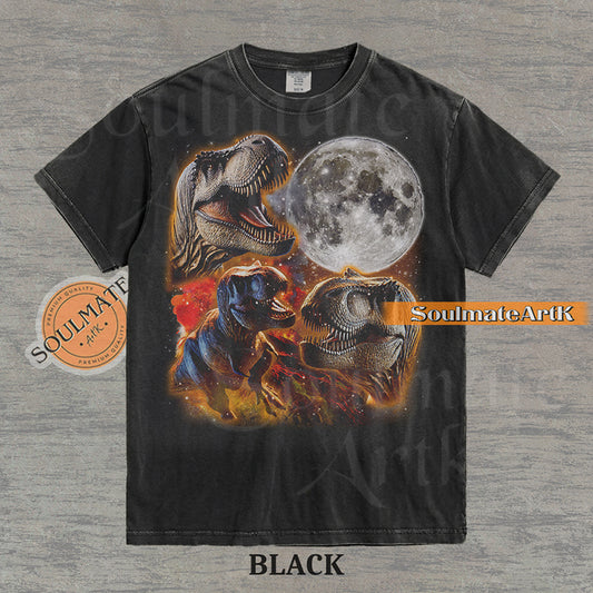 Graphic collage of three T-Rexes next to a large full moon in a starry, colorful space setting on a washed black t-shirt.