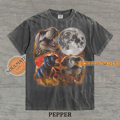 Graphic collage of three T-Rexes next to a large full moon in a starry, colorful space setting on a washed pepper t-shirt.