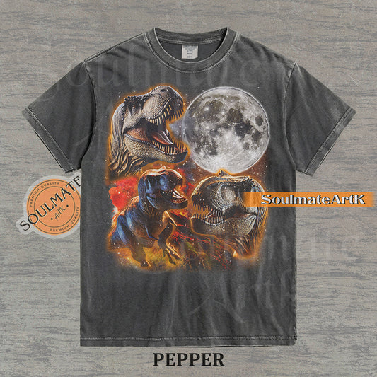Graphic collage of three T-Rexes next to a large full moon in a starry, colorful space setting on a washed pepper t-shirt.