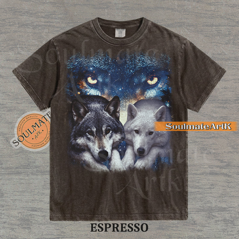 Vintage-style celestial graphic of a timber wolf and arctic wolf resting beneath large glowing wolf eyes in a starry sky on a espresso t-shirt.