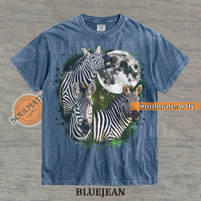 Collage of three zebras in front of a glowing white moon and a green starry nebula on a washed bluejean shirt.
