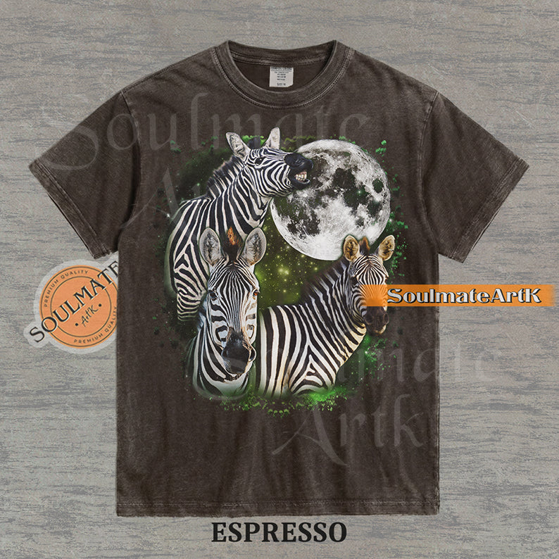 Collage of three zebras in front of a glowing white moon and a green starry nebula on a washed espresso shirt.