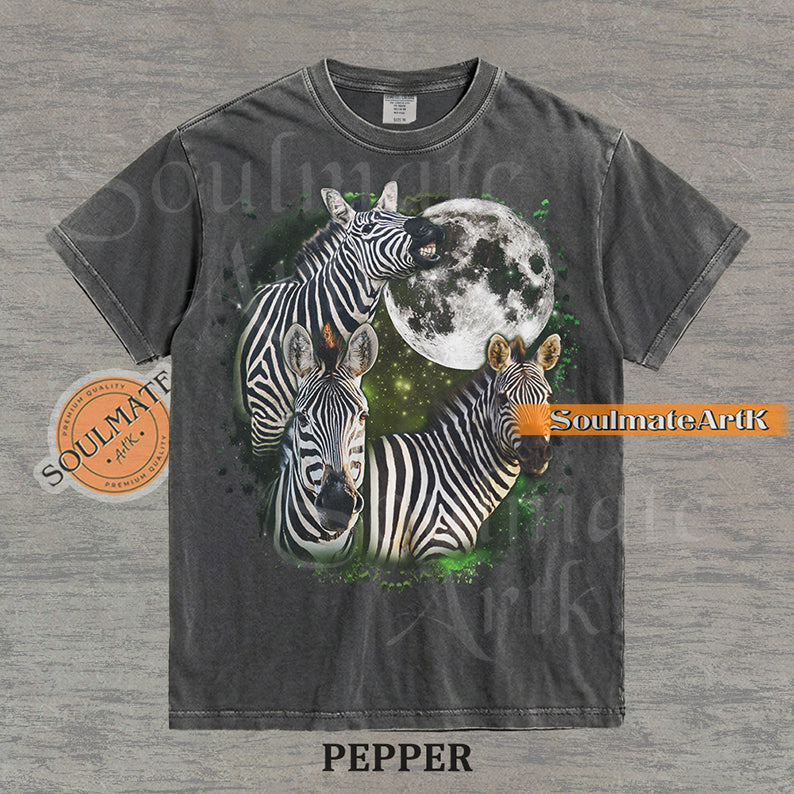 Collage of three zebras in front of a glowing white moon and a green starry nebula on a washed pepper shirt.