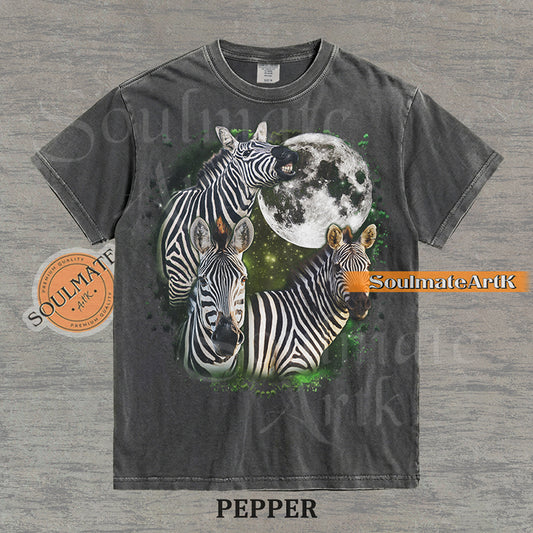 Collage of three zebras in front of a glowing white moon and a green starry nebula on a washed pepper shirt.