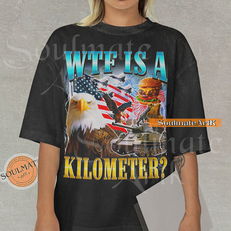 Graphic collage featuring a bald eagle, American flag, fighter jets, a tank, and a burger with bold text reading WTF IS A KILOMETER? on a washed black shirt.