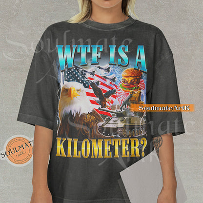 Graphic collage featuring a bald eagle, American flag, fighter jets, a tank, and a burger with bold text reading WTF IS A KILOMETER? on a washed pepper shirt.