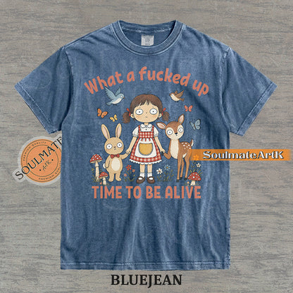 Illustration of a startled girl with a bunny and deer in a forest with the text "What a fucked up TIME TO BE ALIVE" on a washed bluejean t-shirt.